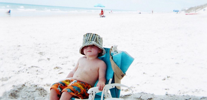 A child sitting on a chair at the beach