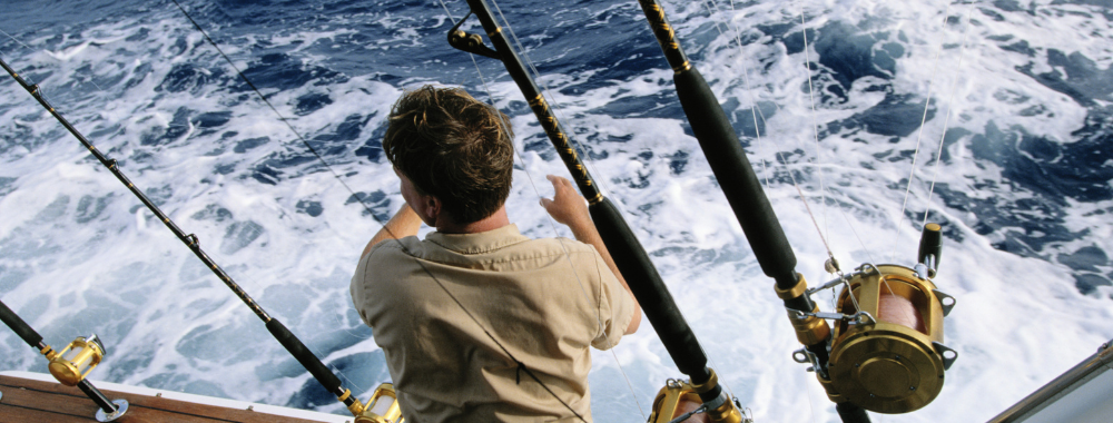 Man surrounded by deep sea fishing poles on a boat