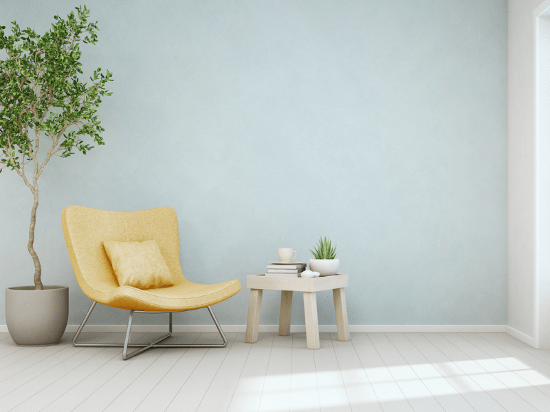A soft colored blue wall with a yellow chair for the perfect color combo with accennt plants