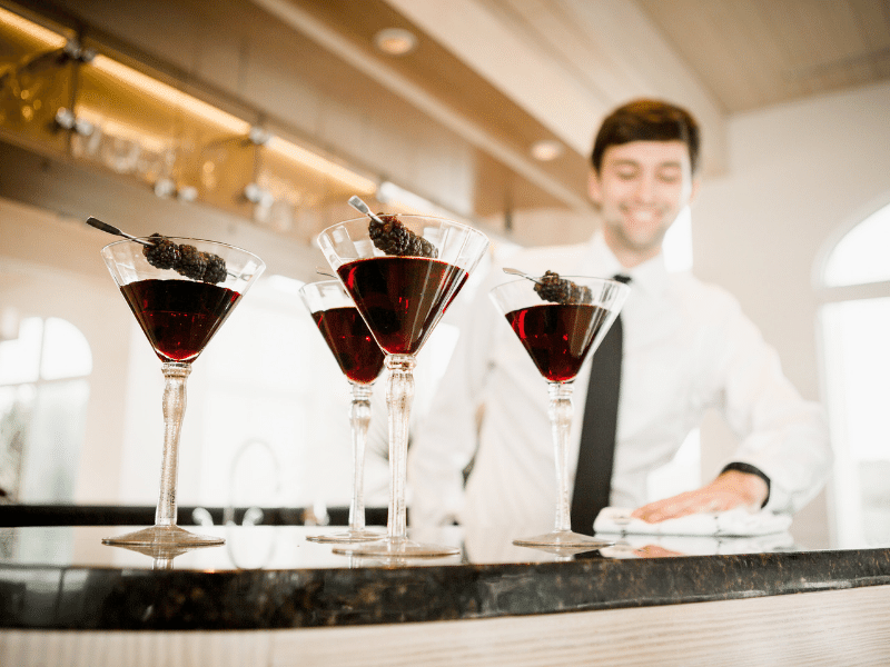 Blackberry adorned cocktails with a bartender ready tp serve them