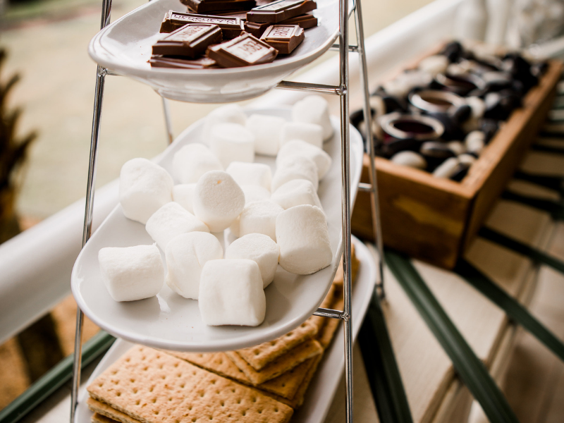 a s'mores buffet table with chocolate squares, marshmallows and graham crackers for guests to enjoy