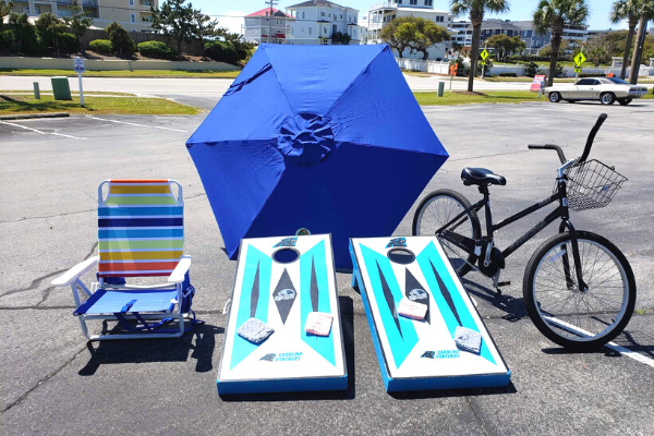 A beach chair, umbrella, bike and corn hole boards on display