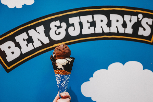An ice cream cone held up in front of the Ben & Jerry's mural