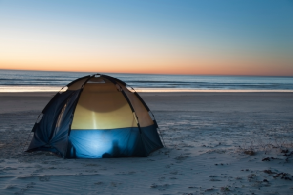 Camping tent on the beach with light inside it