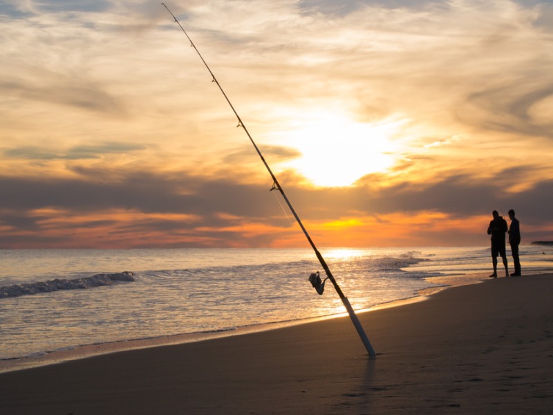 A fishing pole rests of the shoreline of an Emerald Isle beach.